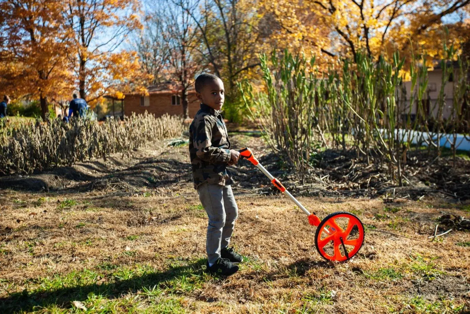 A boy is holding a metal toy in the grass.