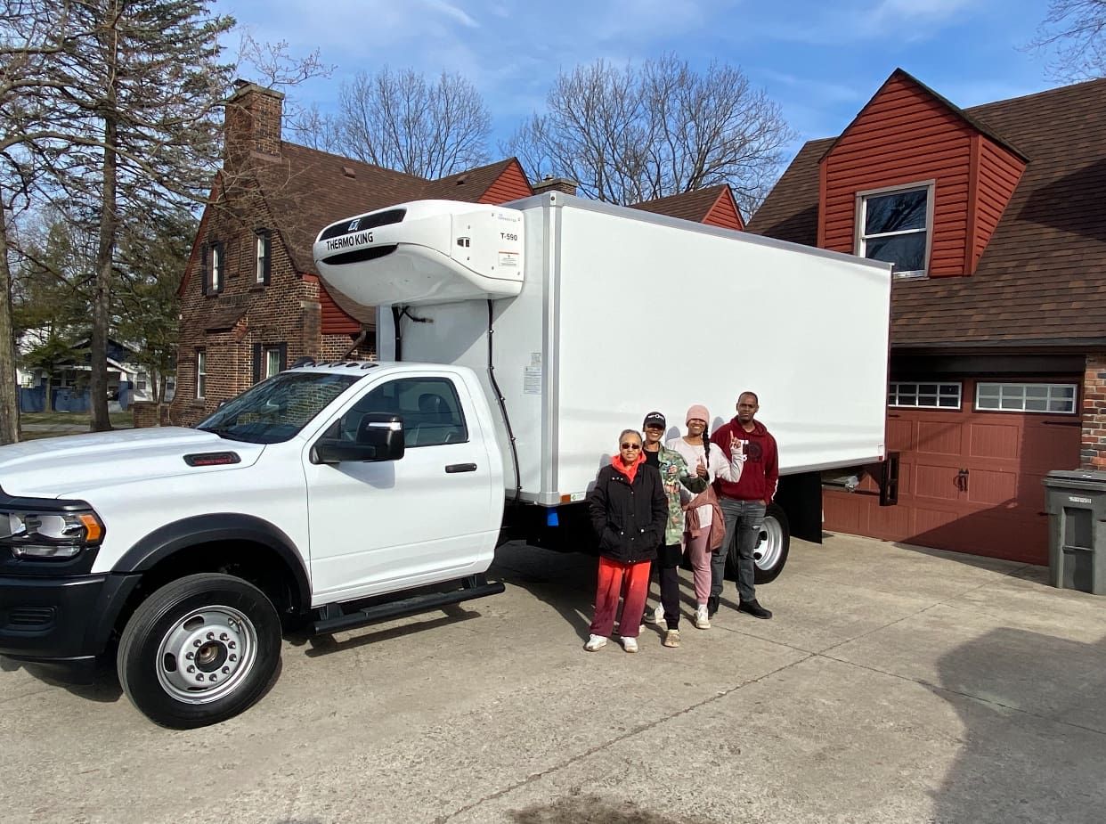 Three people standing in front of a large truck.